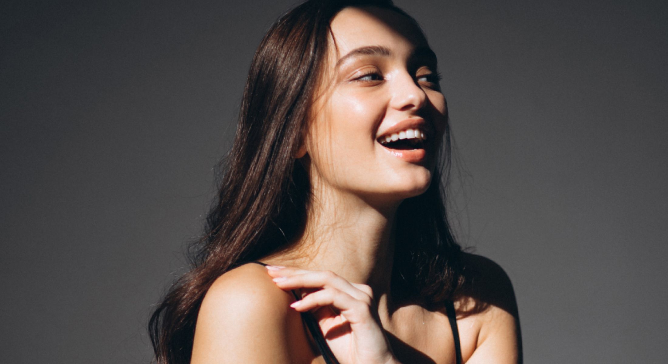 Smiling woman in soft lighting, joyful expression.