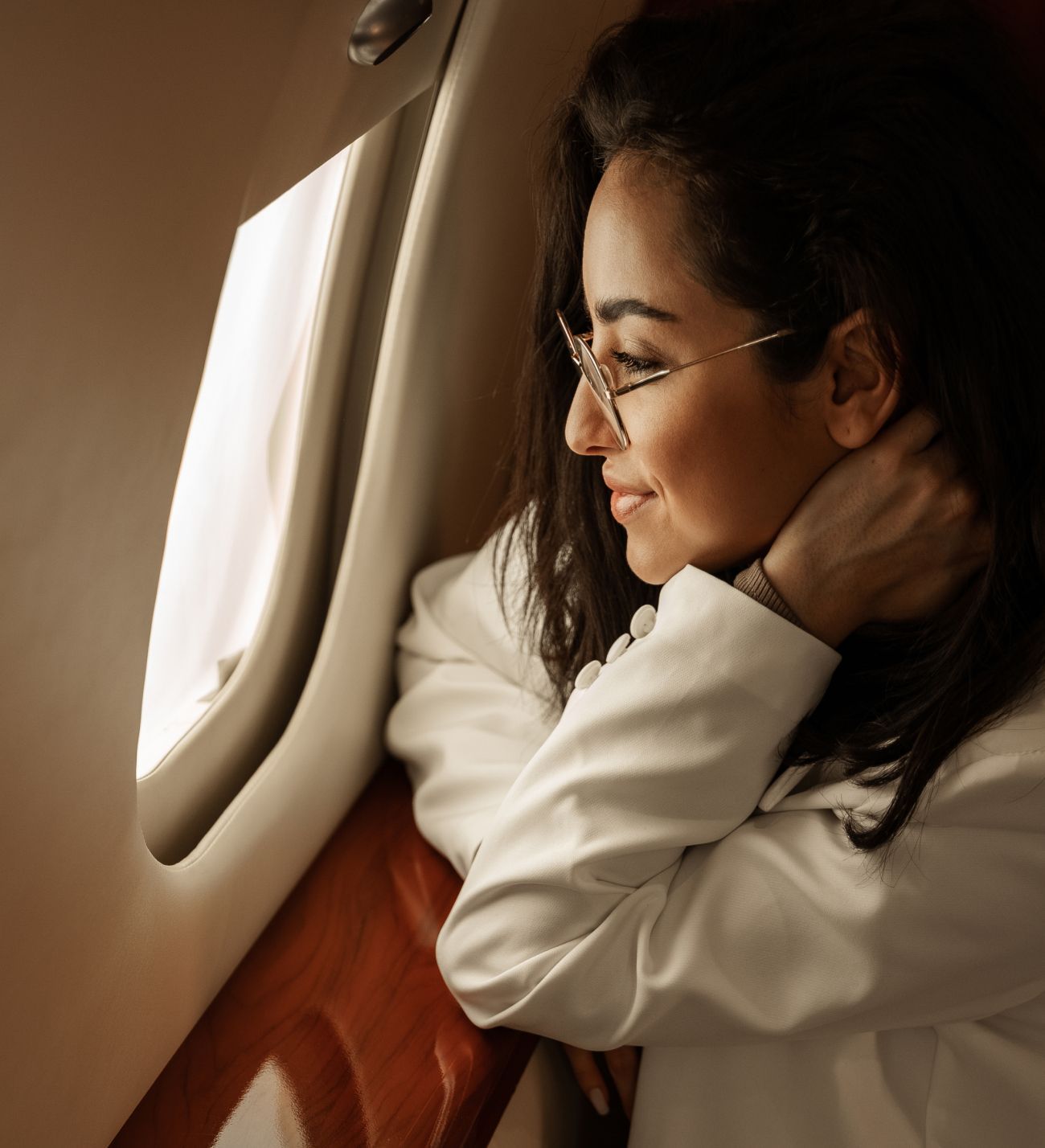 Woman gazing out an airplane window thoughtfully.