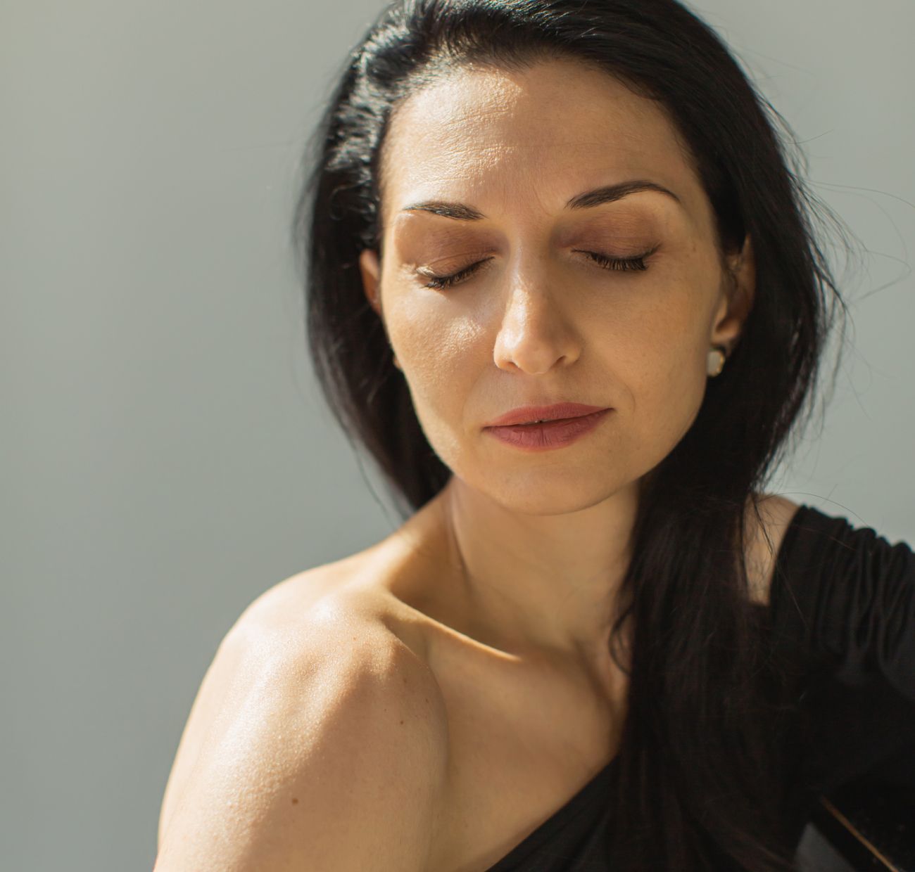 Woman with closed eyes, soft expression, natural light.