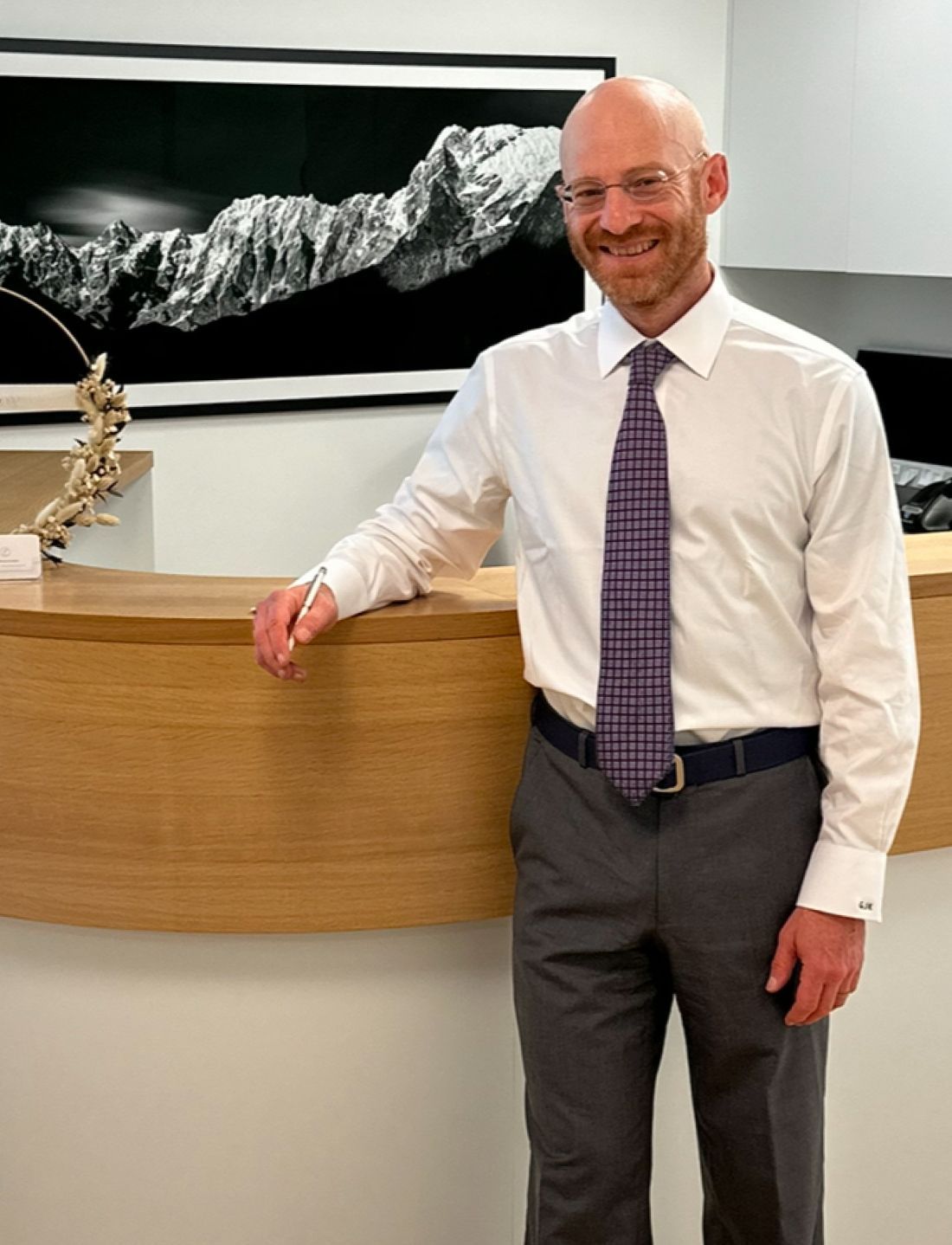 Smiling man in business attire at reception desk.